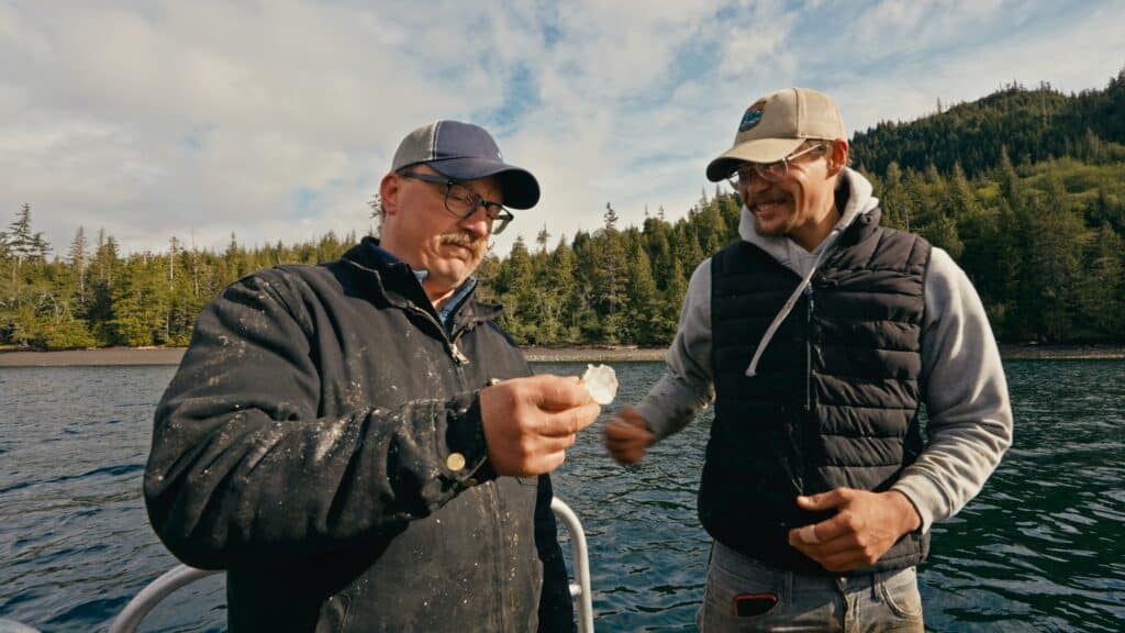 Two men on a boat holding a fish.